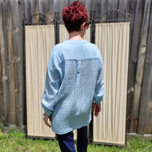Load image into Gallery viewer, Ada-long-sleeve-Vneck-muslin-blouse-features-front-pockets-and-sleeve-tabs-in-ice-blue-worn-with-navy-casual-pants-back-view