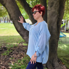 Load image into Gallery viewer, Ada-long-sleeve-Vneck-muslin-blouse-features-front-pockets-and-sleeve-tabs-in-ice-blue-worn-with-navy-casual-pants-side-view