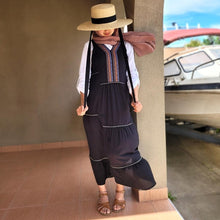 Load image into Gallery viewer, coral-sleeveless-maxi-dress-with-embroidery-detail-on-Vneckline-and-front-bodice-and-wide-tiered-skirt-with-lace-trim-in-black-worn-with-white-shirt-front-view-outdoor-image