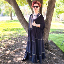 Load image into Gallery viewer, coral-sleeveless-maxi-dress-with-embroidery-detail-on-Vneckline-and-front-bodice-and-wide-tiered-skirt-with-lace-trim-in-black-worn-with-black-cardigan-front-view