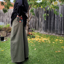 Load image into Gallery viewer, Luna high-waisted, wide leg, brushed cotton, women's pants in khaki, side view showing back pocket floral detail, worn with black tunic