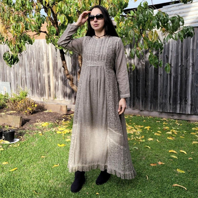 long-sleeve-cotton-maxi-dress-in-mocha-with-eyelet-embroidery-on-front-sides-pintuck-detail-on-chest-lace-frill-at-skirt-hem-and-string-tie-at-waist-back