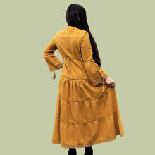 Load image into Gallery viewer, brushed-cotton-flannel-tiered-maxi-dress-in-mustard-showing-bell-sleeves-with-tassel-ties-lace-trim-on-sleeves-and-skirt-hem-and-string-tie-waist-on-dress-back