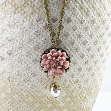 Load image into Gallery viewer, vintage-style-dusty-pink-lotus-flower-bronze-necklace-with-swarovski-pearl-drop-detail-hanging-from-textured-bowl