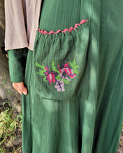 Load image into Gallery viewer, Green dress with floral embroidery and pink trim detail on front pocket, worn by a person outdoors.
