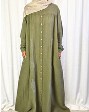 Load image into Gallery viewer, Front view of woman wearing long khaki dress with buttons and embroidery against a white curtain background
