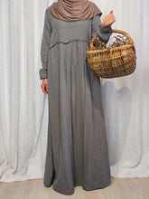 Load image into Gallery viewer, Woman wearing a long grey dress holding a woven basket in front of a white curtain
