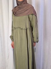 Load image into Gallery viewer, Woman wearing a long olive green dress with a light brown hijab against a white curtain background

