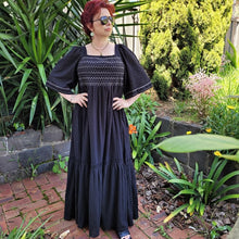Load image into Gallery viewer, manolya-shirred-maxi-dress-with-bell-sleeves-square-neckline-empire-waist-skirt-with-ruffled-hem-in-black-outdoor-front-view-image-in-front-of-palm-tree
